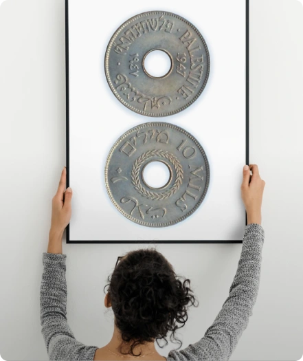A collector hanging a framed pair of historical coins